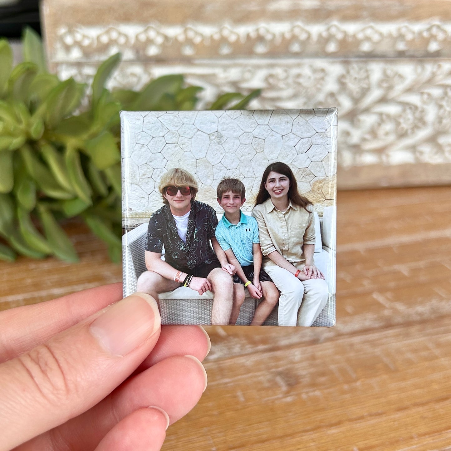 2x2" photo magnet held between two fingers with 3 smiling children on it