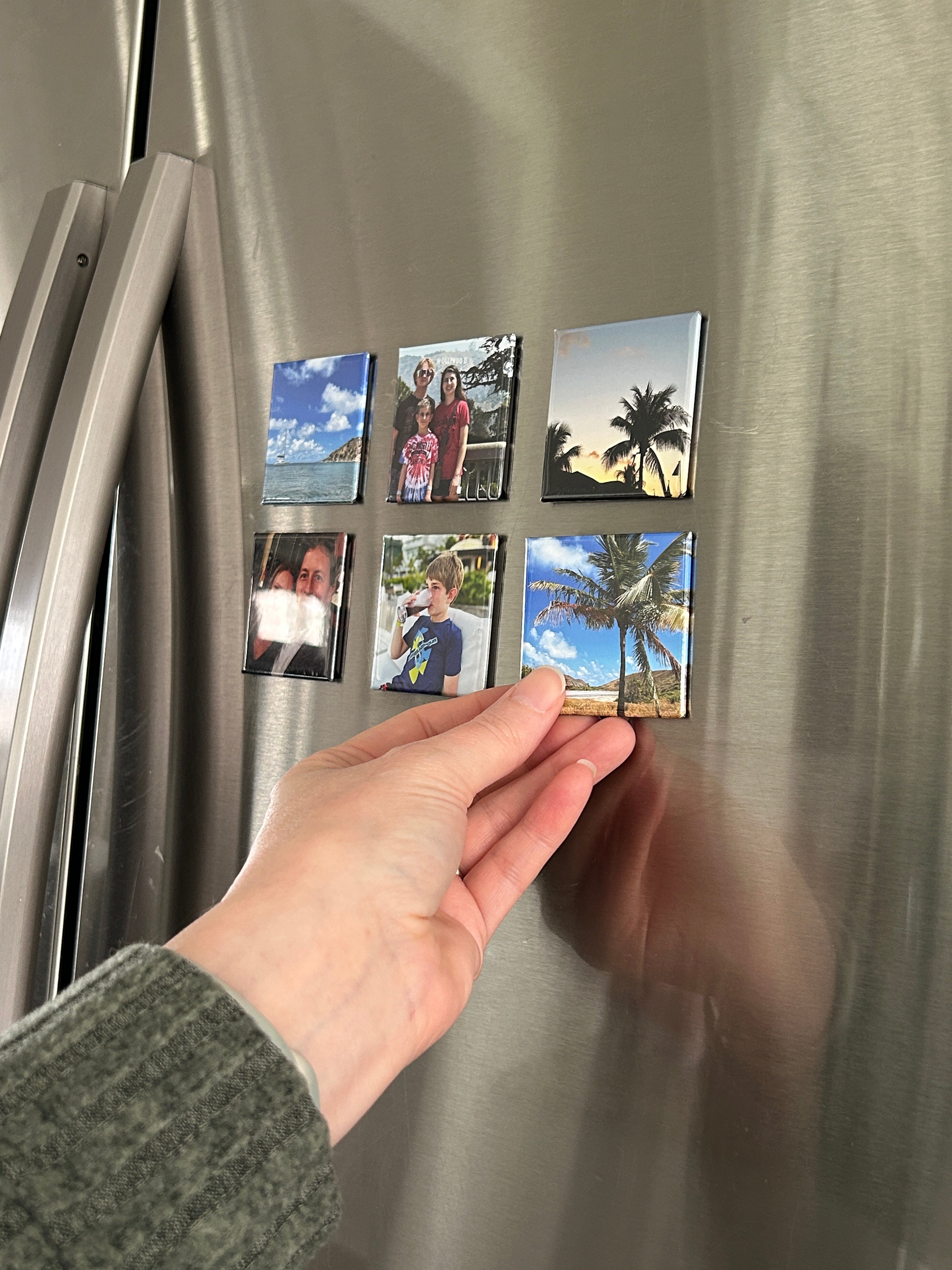 Hand placing small square images on a metallic surface