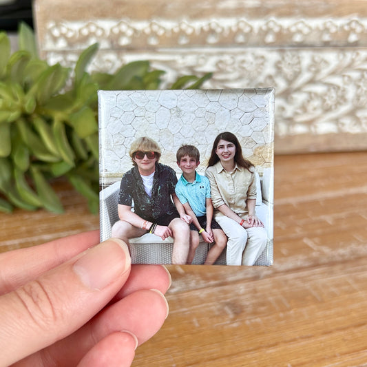 2x2" photo magnet held between two fingers with 3 smiling children on it